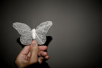 A hand holding white butterfly on dark background symbolizing salvation from sadness and depression with copy space