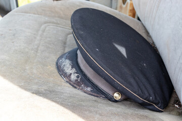Old shabby postman cap on a car seat as a symbol of outdated format of post services