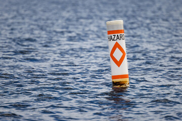 Hazard safety buoy alerting boaters to navigation danger. Nautical warning caution float. - obrazy, fototapety, plakaty