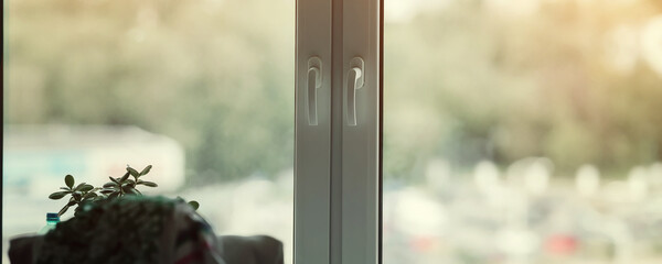 Closed plastic window frame of hotel room with clothing on chair. View through windows glass.