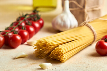Food background, healthy mediterranean concept of
organic ingredients.
Still life with olive oil,tomato,garlic,basil leaves and raw pasta on beige background. Top wiev with copy space