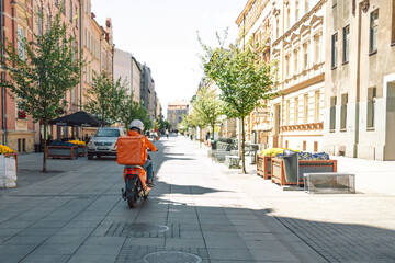 Food delivery concept. 24 hours delivery service from cafes and restaurants. Takeaway, delivery boy on scooter with orange backpack driving fast. Courier delivering food on motorbike © Shi 