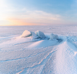 Winter landscape. Snowdrifts on the ice surface during sunset. © Tishina