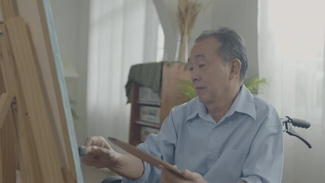 Artist concept of 4k Resolution. Asian man painting in the living room. Artist is creating work. Leisure activities and hobbies.