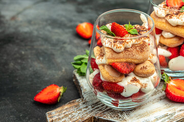 Tiramisu. Homemade tiramisu with fresh strawberry, mascarpone and mint in glass on dark background....