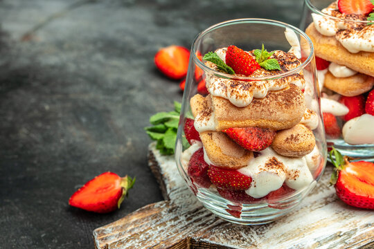 Tiramisu. Homemade tiramisu with fresh strawberry, mascarpone and mint in glass on dark background. Vegan lactose free dessert, Recipe of healthy organic decert