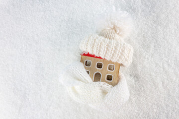 Figure of house and warm clothes on the snow background. Heating season concept. European energy crisis concept. Copy space. Top view..