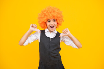 Birthday kids party. Funny kid in curly clown wig isolated on yellow background. Excited face,...