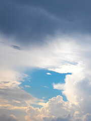 Dark and light clouds in the blue sky during sunset. A patch of blue sky peeks through the clouds