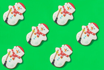 Christmas gingerbread in the shape of a snowman on the green background. Top view.