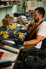 A disabled manufacturer in wheelchair is using tool to put metal bars together.