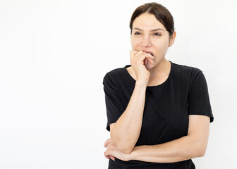 Afraid Caucasian woman biting her fingers. Woman wearing black T-shirt standing on white background, feeling stress or shock. Negative emotion, expression, studio shot concept