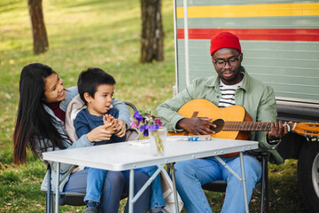 The fun family plays guitar and sings the song together in front of the motor home.