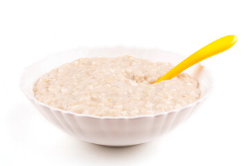 Oatmeal porridge for the baby in a bowl (plate), a yellow spoon on a white isolated background. The first complementary food, baby nutrition. Healthy breakfast. Template, design.
