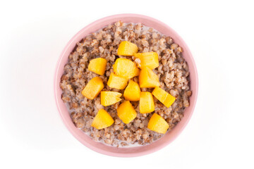 Buckwheat porridge with milk and juicy peach in a pink bowl (plate) on a white isolated background. Template for the design. Porridge for a child (baby). Healthy breakfast.