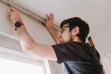 Man attaching a curtain track at home renovations.