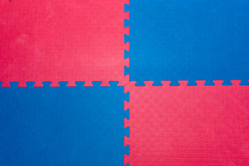 Eva foam rubber floor puzzle mats texture, colorful floor mat background. Multicolored soft elements. Blue and pink puzzles connected