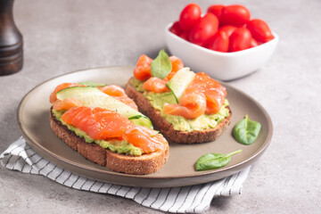 Two tasty open salmon sandwiches with avocado and cucumber. Morning healthy breakfast. Top view.