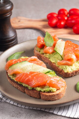 Two tasty open salmon sandwiches with avocado and cucumber. Morning healthy breakfast. Top view.