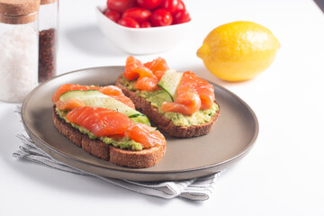 Two tasty open salmon sandwiches with avocado and cucumber. Morning healthy breakfast. Top view.
