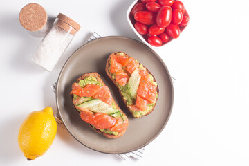 Two tasty open salmon sandwiches with avocado and cucumber. Morning healthy breakfast. Top view.