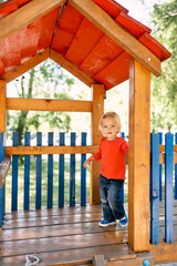 Little girl stands on a wooden platform under a canopy at the playground. High quality photo