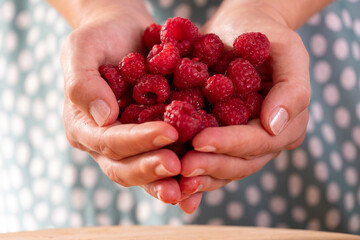 Woman holding ripe raspberries in hands