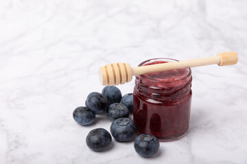 A jar of blueberry honey on a textured background. Cold medicine. Useful fortified jam for health and beauty. Vegetarian diet organic product. Copy space.place for text