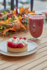 Bright aesthetic healthy autumn table - pink strawberry smoothie and french tart at the terrace outside
