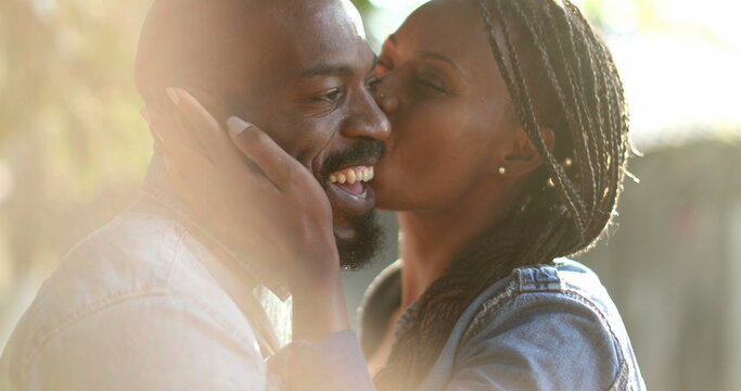 Candid African Couple Together Outside At Park. Woman Kissing Man In Cheek Outside