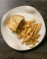 Half a grilled chicken sandwich with seasoned French fries.