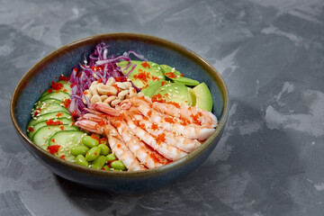 Top view on poke salad with red shrimps and green vegetable in the bowls on gray background. Copy space.