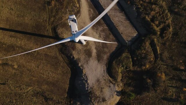 Aerial top down view on a windmill, drone flies over rotating blades of wind turbine