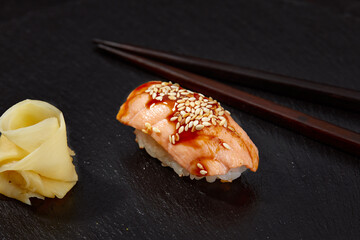 Sushi with smoked eel and sesame seeds on a black background. Japanese dish Unagi sushi.