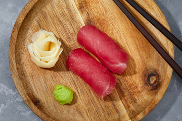 View from above of pieces of tuna on wooden board and ginger with wasabi to be cut and prepare sushi.