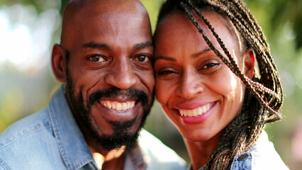 African couple kissing outside, two people smiling at camera