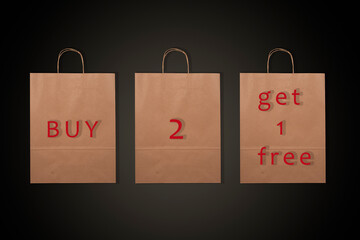 Paper bags with words Buy 2 Get 1 Free and black background