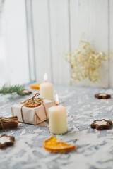 Christmas still life on the windowsill. Concrete background, gifts, candles and garlands