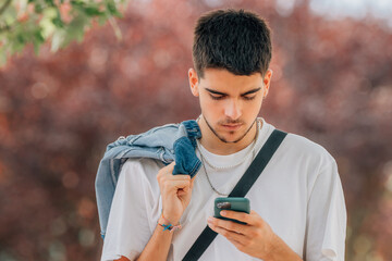Fototapeta premium young man looking at mobile phone in the street