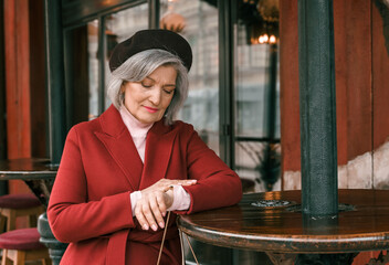 Elderly senior woman walking at cafe table in restaurant. Old retired aged lady on walk on city street. Stylish elegant elder person pensioner. Quite calm happy years in metropolis