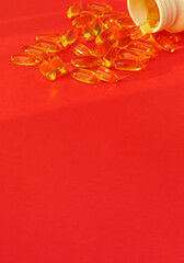 Fish oil pills. Omega 3 gel capsules on red background