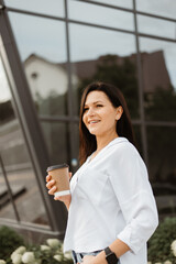 Coffee in the hands of a businesswoman on the street near the building