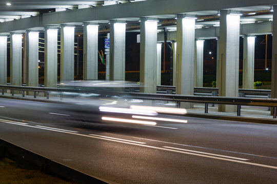 The Car Moves Under The Overpass In The Evening..