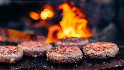Cook grills veal burger cutlets open fire BBQ. Turns meat over with tongs. Concept Street food