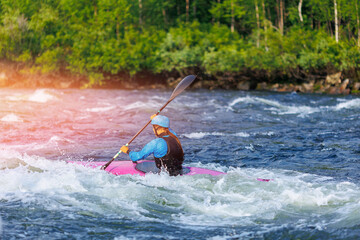 Whitewater kayaking, extreme sport rafting. Young woman in kayak sails mountain river