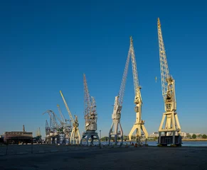 Fotobehang Old harbor cranes in early morning sunlight. The cranes are part of the collection of the MAS museum. © Erik_AJV