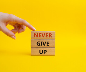 Never give up symbol. Concept words Never give up on wooden blocks. Beautiful yellow background. Businessman hand. Business and Never give up concept. Copy space.