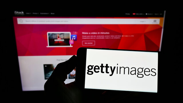 Stuttgart, Germany - 12-12-2021: Person holding mobile phone with logo of stock photo provider Getty Images Inc. on screen in front of business web page. Focus on phone display.