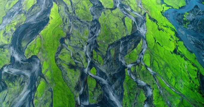Shot by drone of small creeks and riverbed covered with green moss.