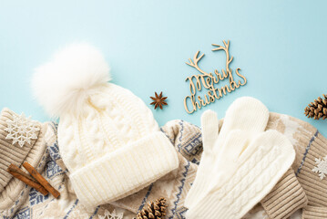 Winter holidays concept. Top view photo of merry christmas wooden text white mittens bobble hat knitted sweater snowflakes pine cones anise and cinnamon sticks on isolated pastel blue background - Powered by Adobe